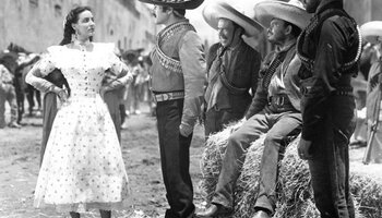A woman stands defiantly before a group of men. 