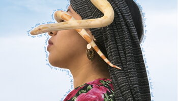 Woman with a snake around her head 