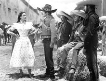 A woman stands defiantely in front of a group of men
